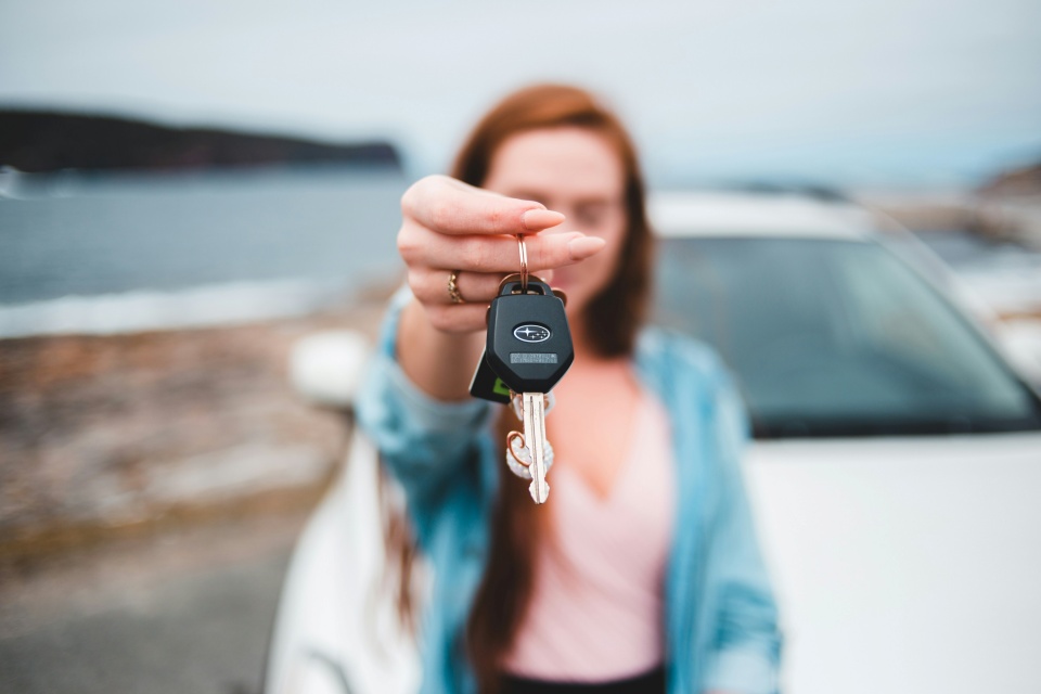 Jeune femme montrant cl&eacute; de voiture